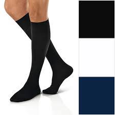 A person wearing a black 8-15mmHg compression sock for mild relief of aches and pains.