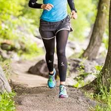 A runner wearing black sleeves to reduce muscle soreness and provide support for below the knee while running to avoid injury and protect the skin