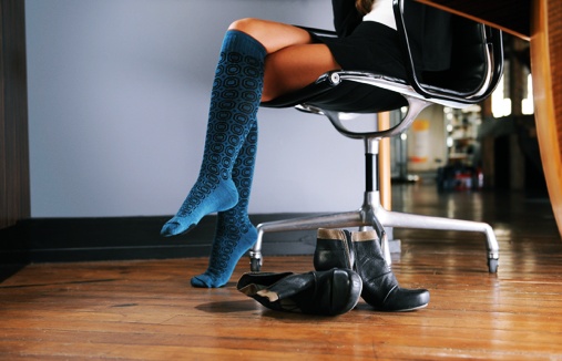 Woman in an office wearing knee high colorful compression stockings