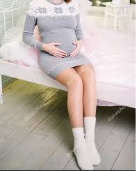 A pregnant person is wearing white color socks.  