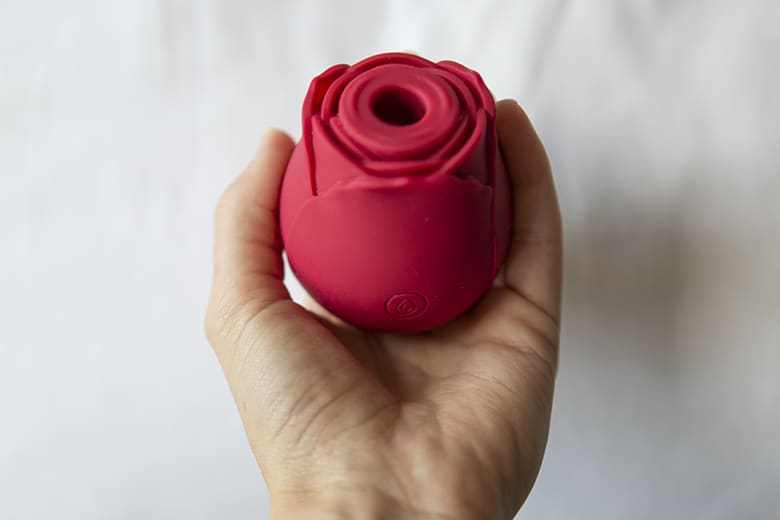 Picture of a Rose Toy in a woman's hand. The rose toy is a sex toy that uses suction to vibrate the clitoris and cause orgasm.