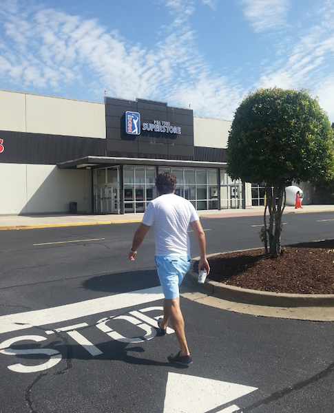 A man walking into supermarket holding a cup of coffee