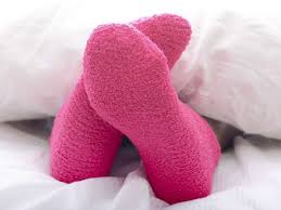 A picture of a person's feet in pink socks laying in bed