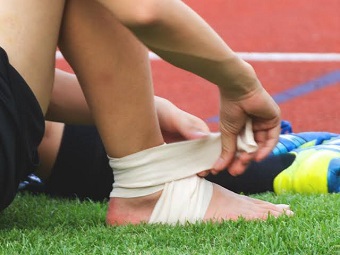 sportsman wrapping compression bandage after ankle injury