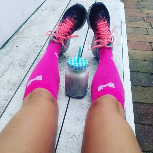 a woman wearing pink compression socks and running shoes