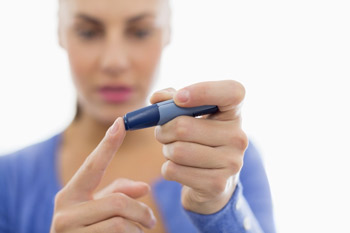 a woman in blue shirt demonstrating the proper use of a lancet when extracting blood for use with a blood sugar monitor