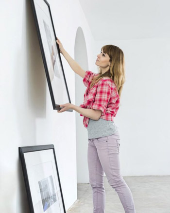 Woman Hanging A Picture on the Wall