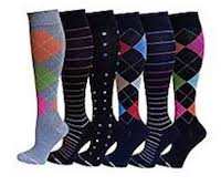 Six compression stockings with varying tux designs that are either grey or black with brightly colored squares on them of orange, pink, blue and green. There are also black stockings with stripes and spots.