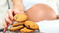 Pregnant woman reaching for a cookie.