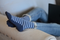 person-wearing-blue-stripped-compression-socks-with-feet-elevated-to-prevent-peripheral-edema