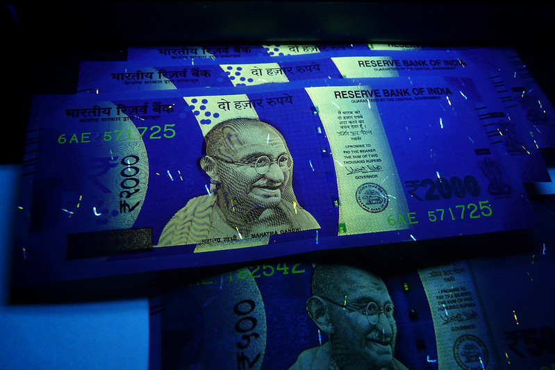 Portions of a 2000 Rupee Indian banknote currency glows under the light when exposed to UV light