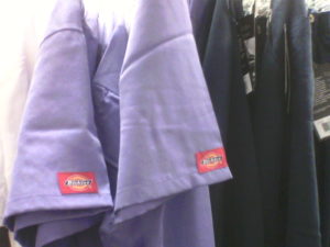 Scrubs are a required uniform for nurses. Purple and blue scrubs are hanging in a closet. Compression stockings are another essential part of the wardrobe for nurses.