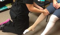 a person helping a patient to wear compression stockings