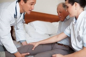 doctors treating a senior man with knee pain with compression socks knee high