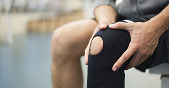 Man holding his knee while wearing a knee sleeve