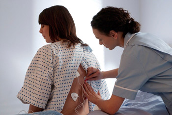 Hospital staff applying tens unit at the back of a female patient