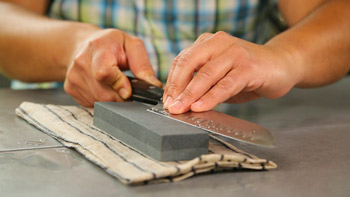 Woman using whetstones to hone a knife